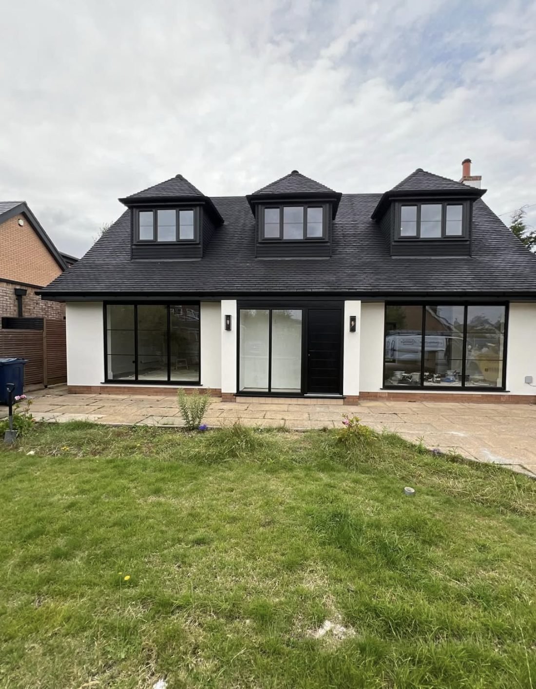 Rear of a chalet house in white render with dormers and wide glazing