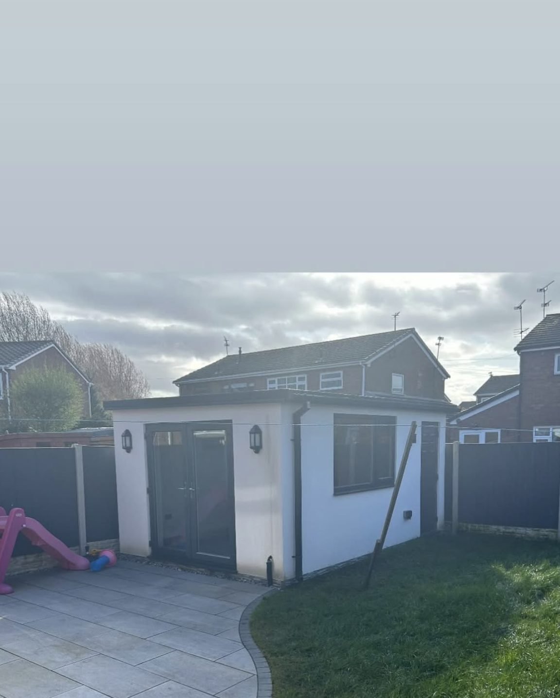 Small rendered garden building with a grey door