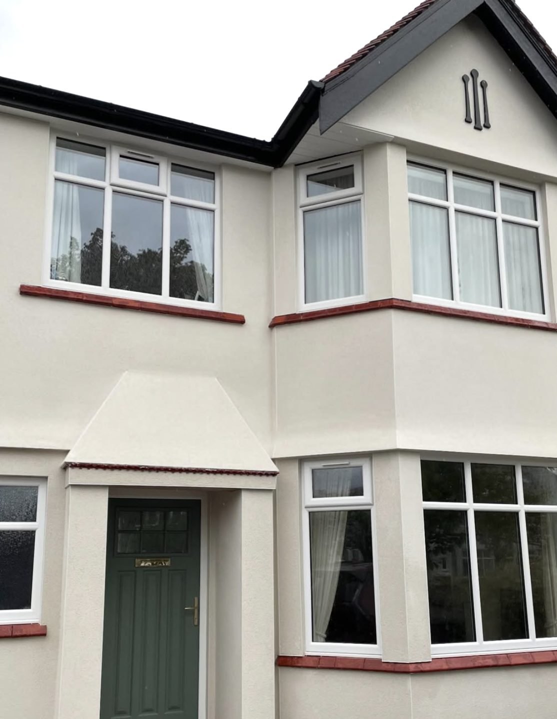 1930s semi with curved bays in cream render and red tile sills