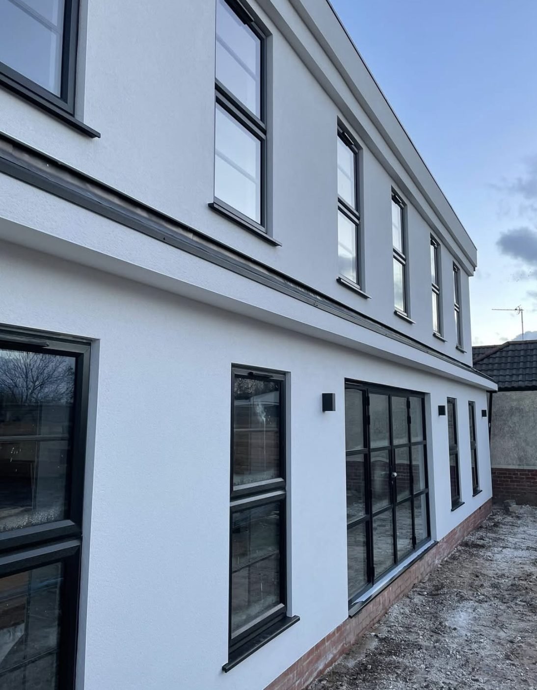 Long side elevation in white render with a dark band and black windows
