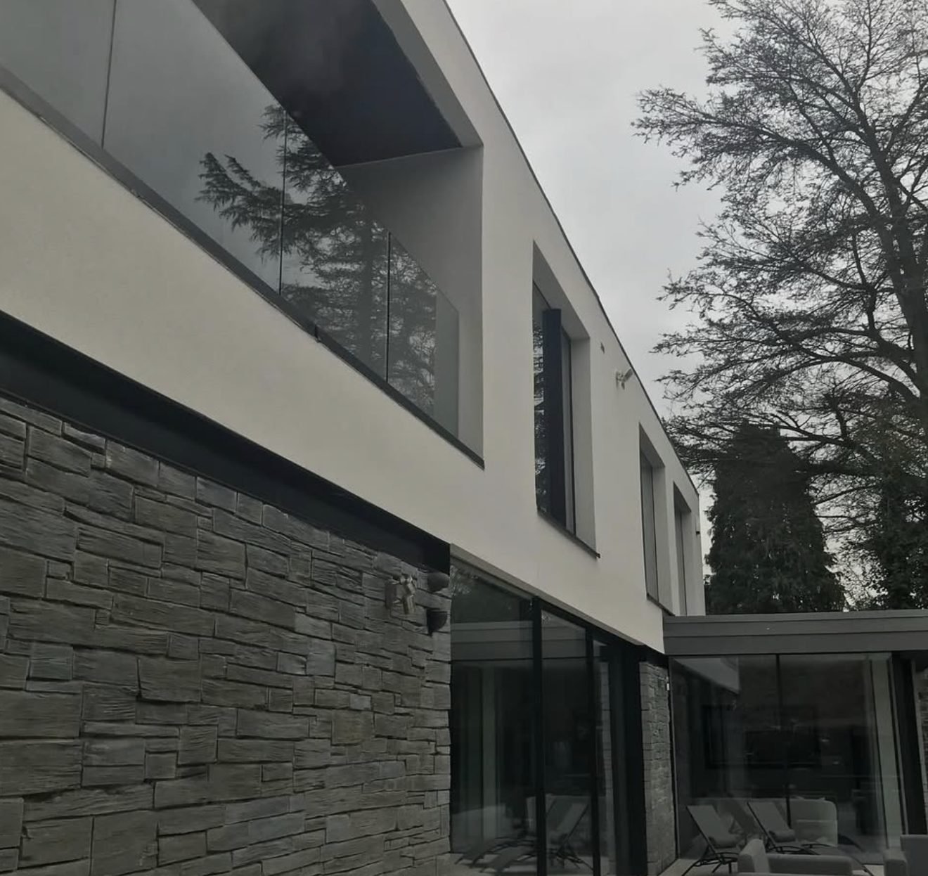 Modern house with white render above dark stone cladding