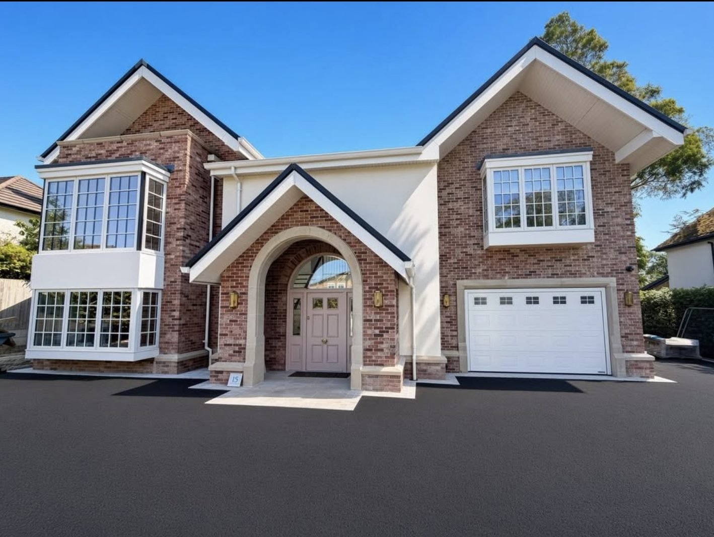 New house with cream render panels between red brick gables