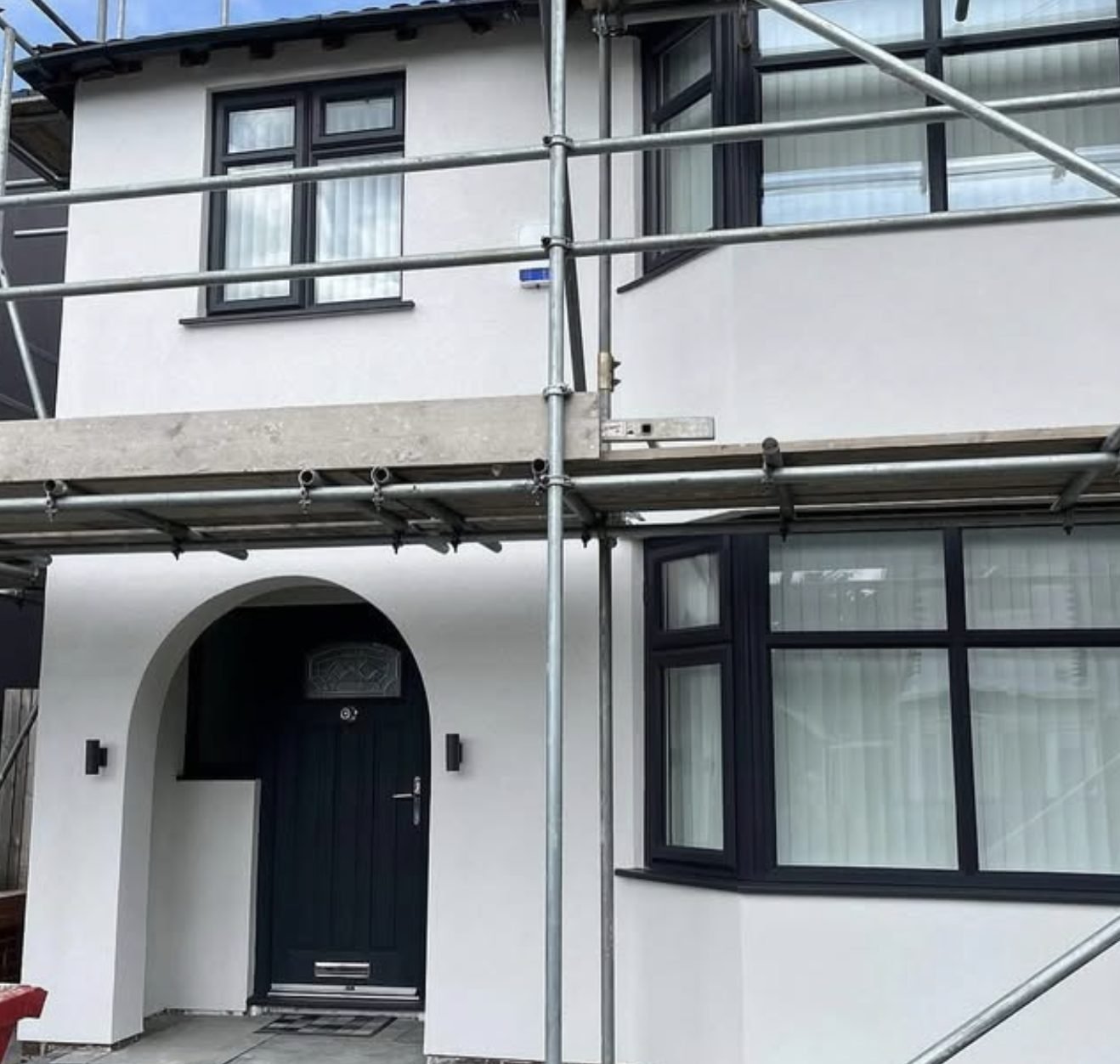 Semi-detached house in new white render with scaffolding up