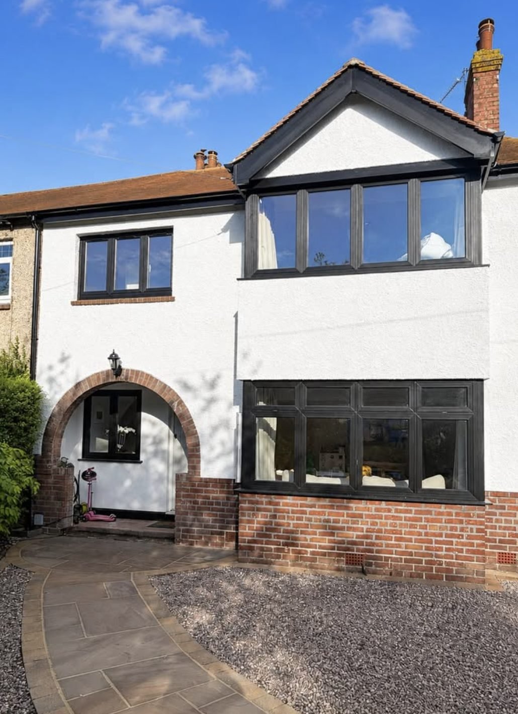 Terraced house in white render with a red brick porch arch