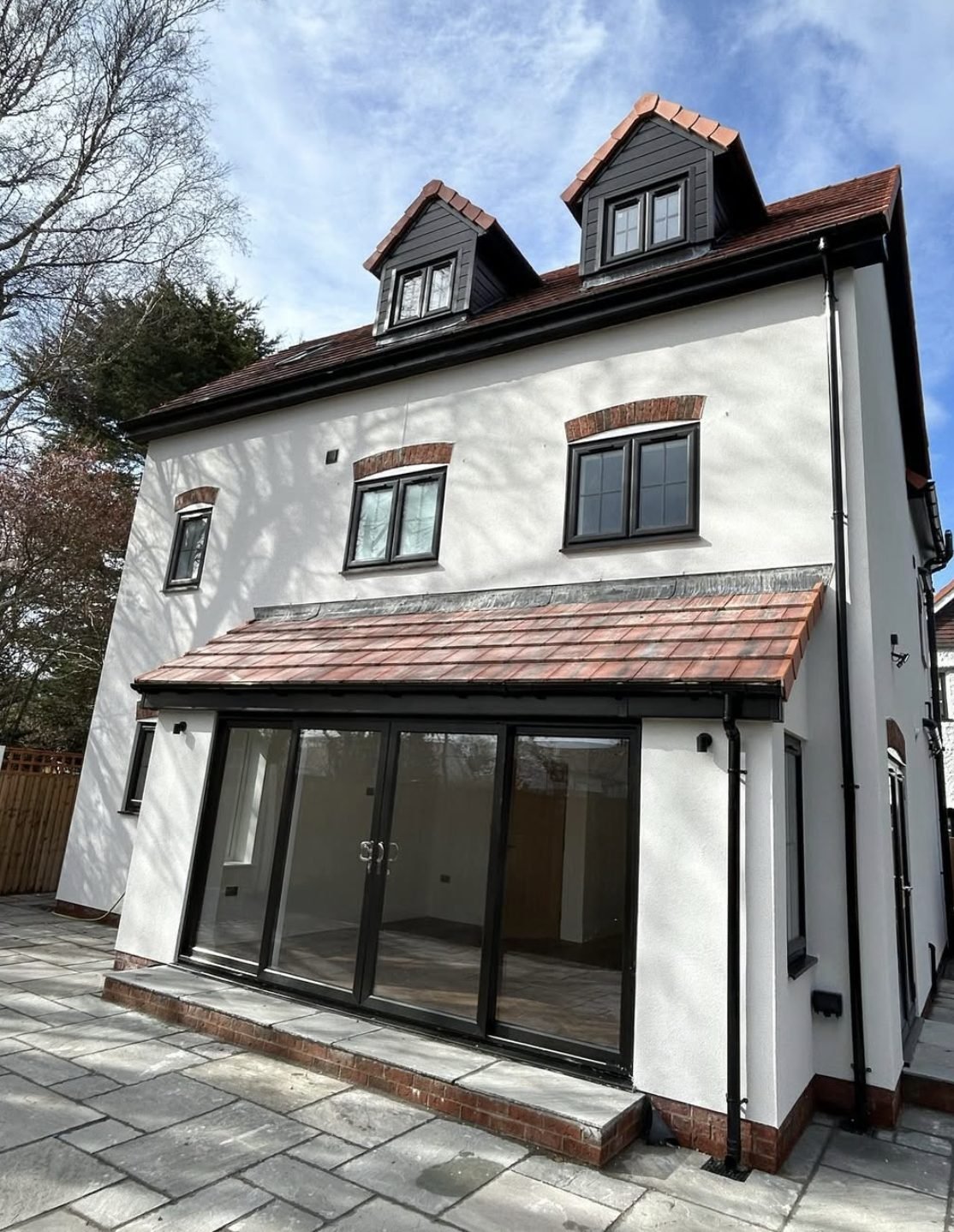 Three-storey back wall in white render with dormers and a tiled extension